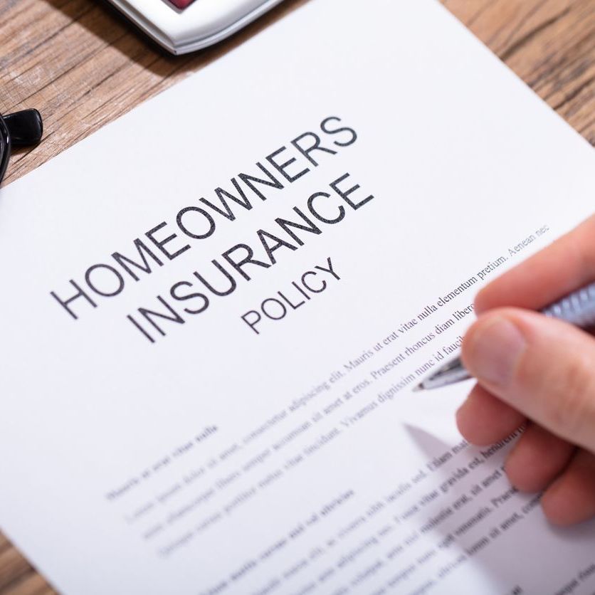 A person is signing a homeowners insurance policy