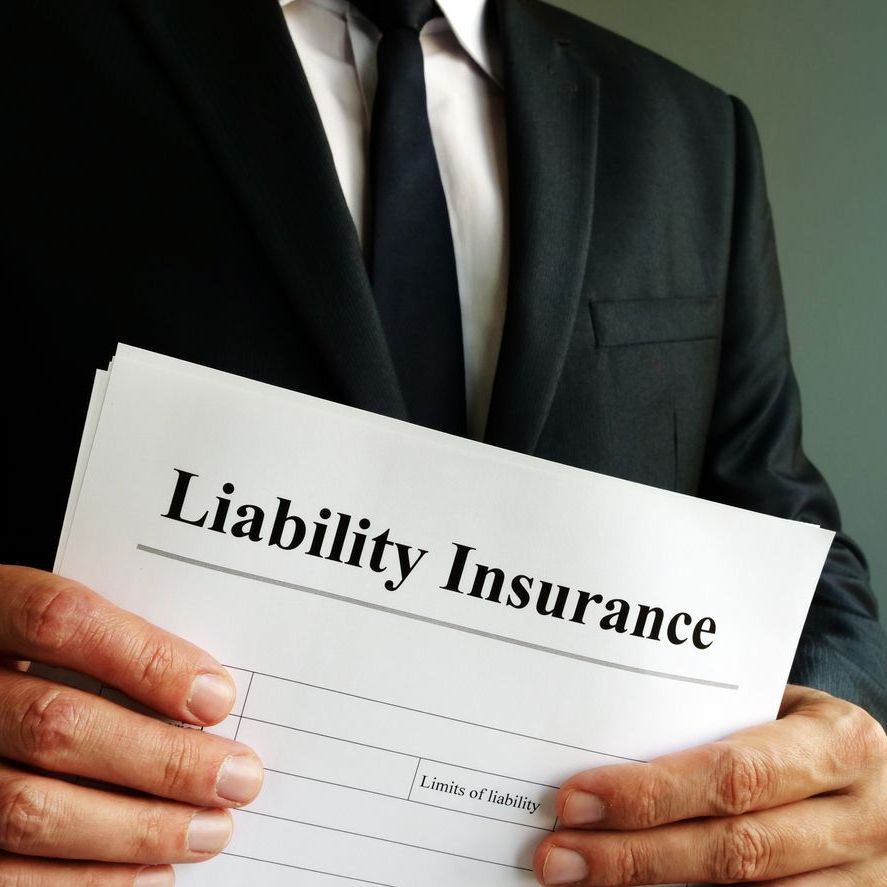 A man in a suit and tie is holding a liability insurance form