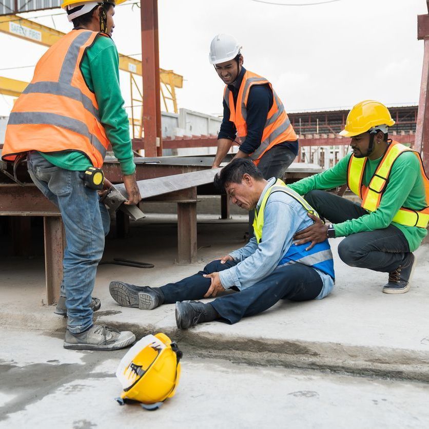 A group of construction workers are helping a man who is laying on the ground.