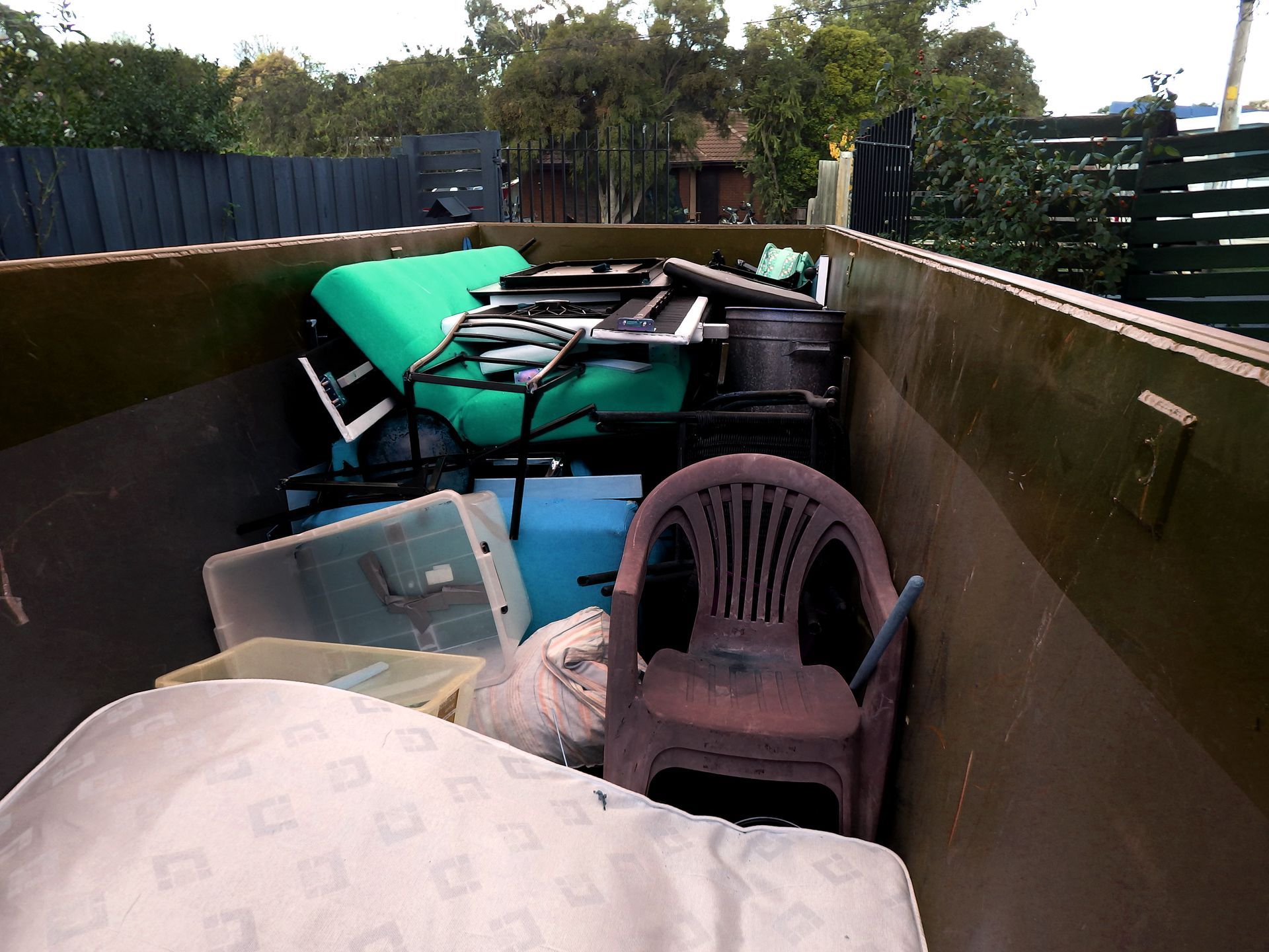 A dumpster filled with furniture and a chair