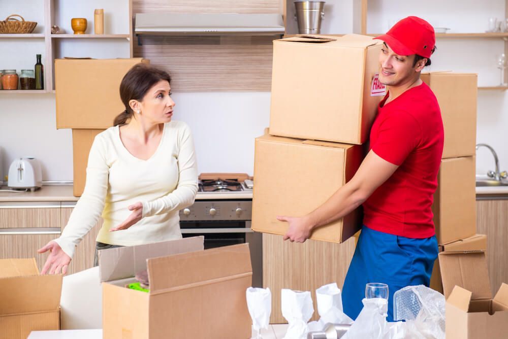 A Man Is Carrying Boxes In A Kitchen While A Woman Looks On — Uplift Removals in Cairns, QLD