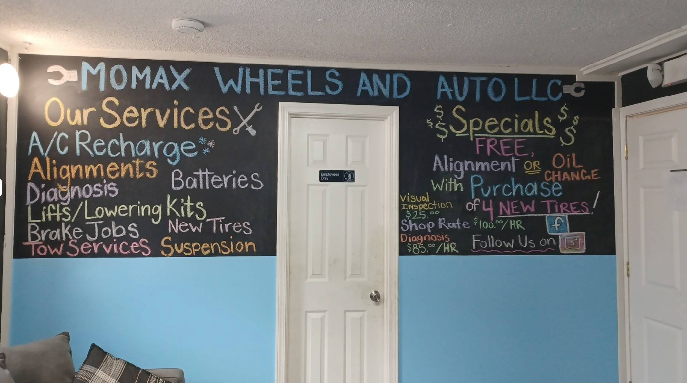 Auto shop wall sign listing services and specials on a blue-and-black interior wall | Momax Wheels and Auto LLC