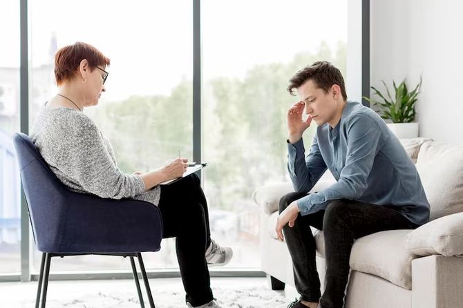 Therapist listening to a man on a couch in a bright 상담 room