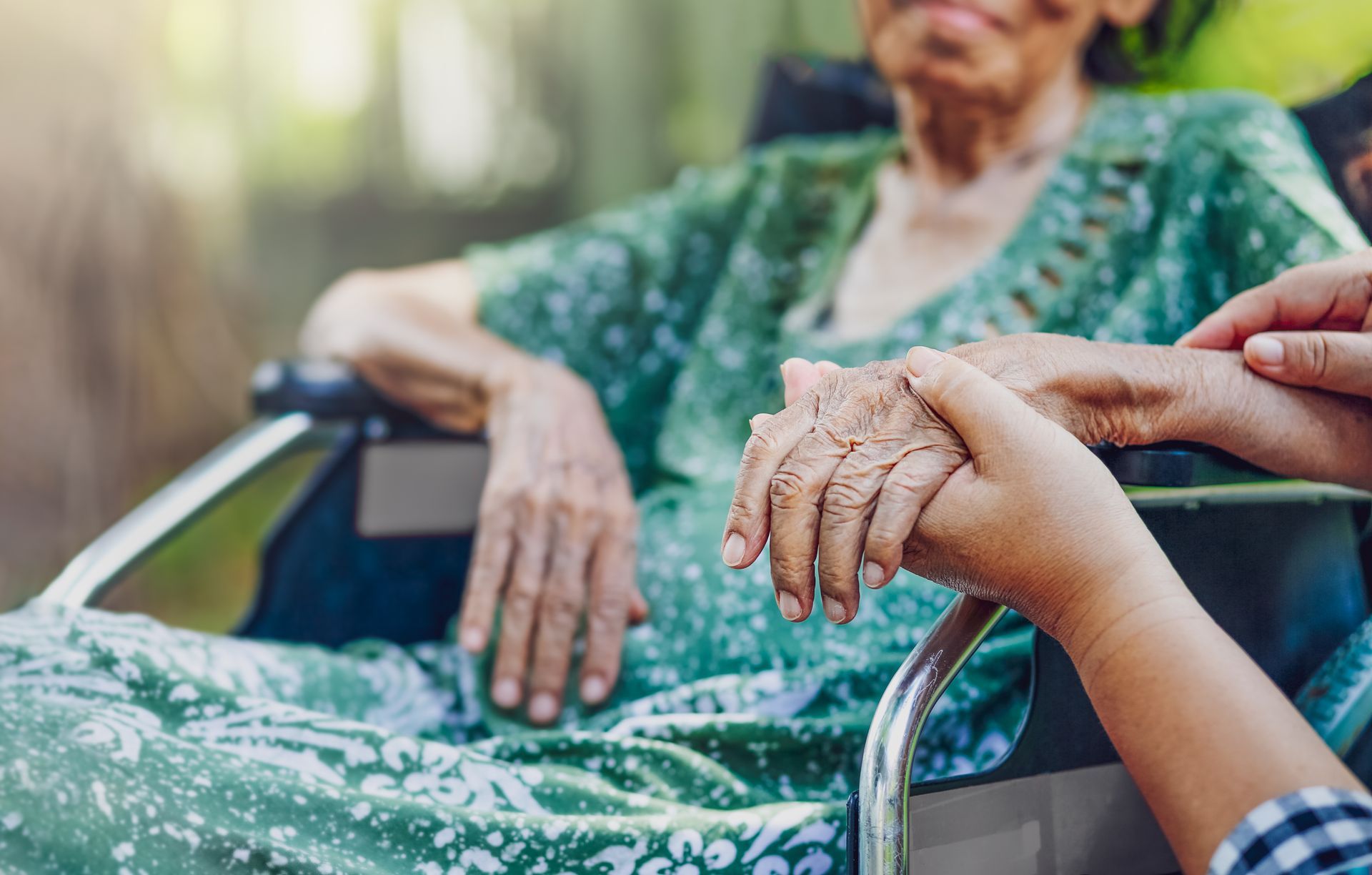 Person in wheelchair holds hands with another person. Outdoors. Person in wheelchair holds hands with another person. Outdoors.