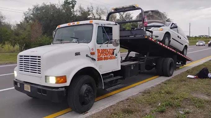 Tow truck with a white car loaded on the flatbed, alongside a highway. Tow truck with a white car loaded on the flatbed, alongside a highway.