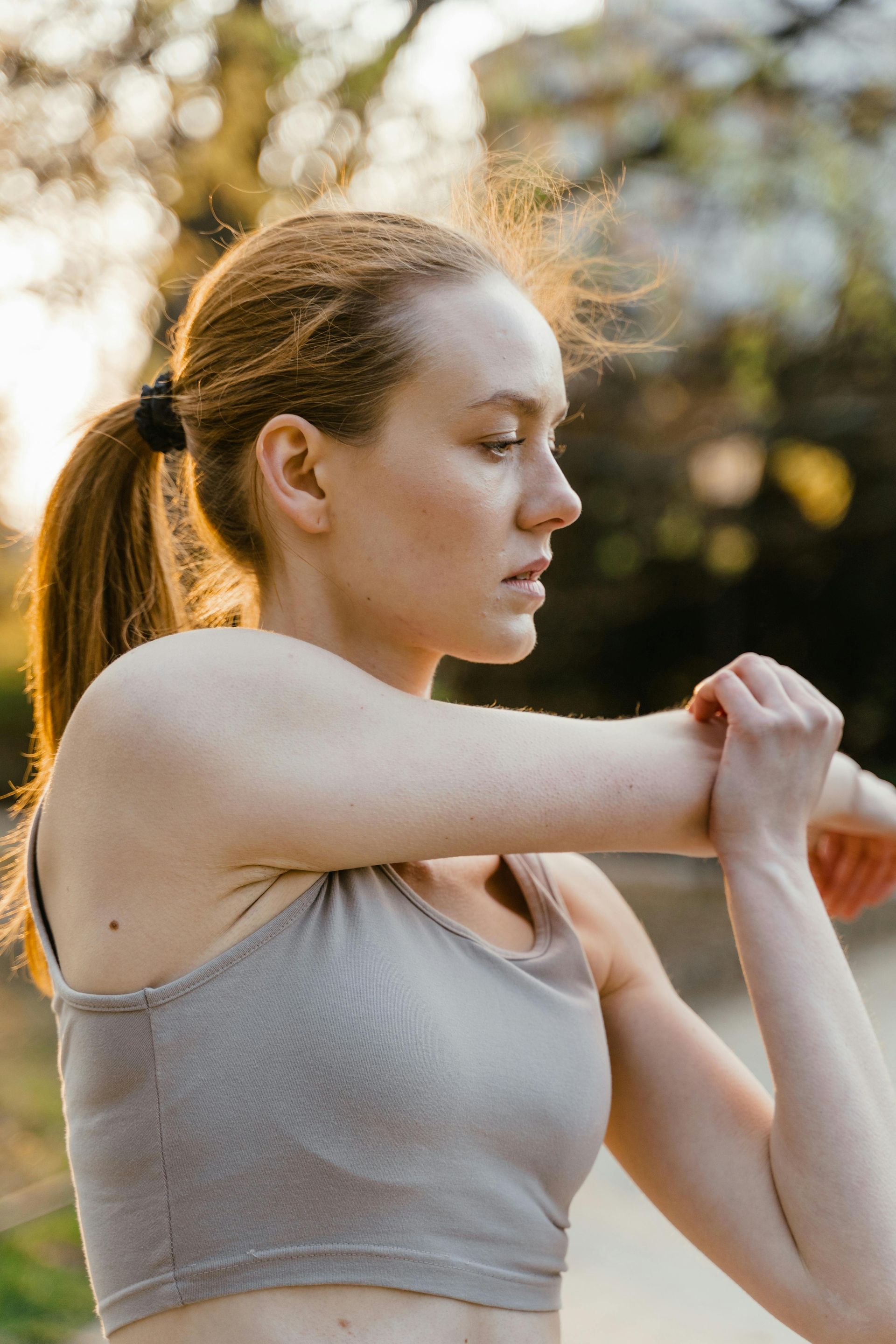 A woman in a sports bra is stretching her arm.