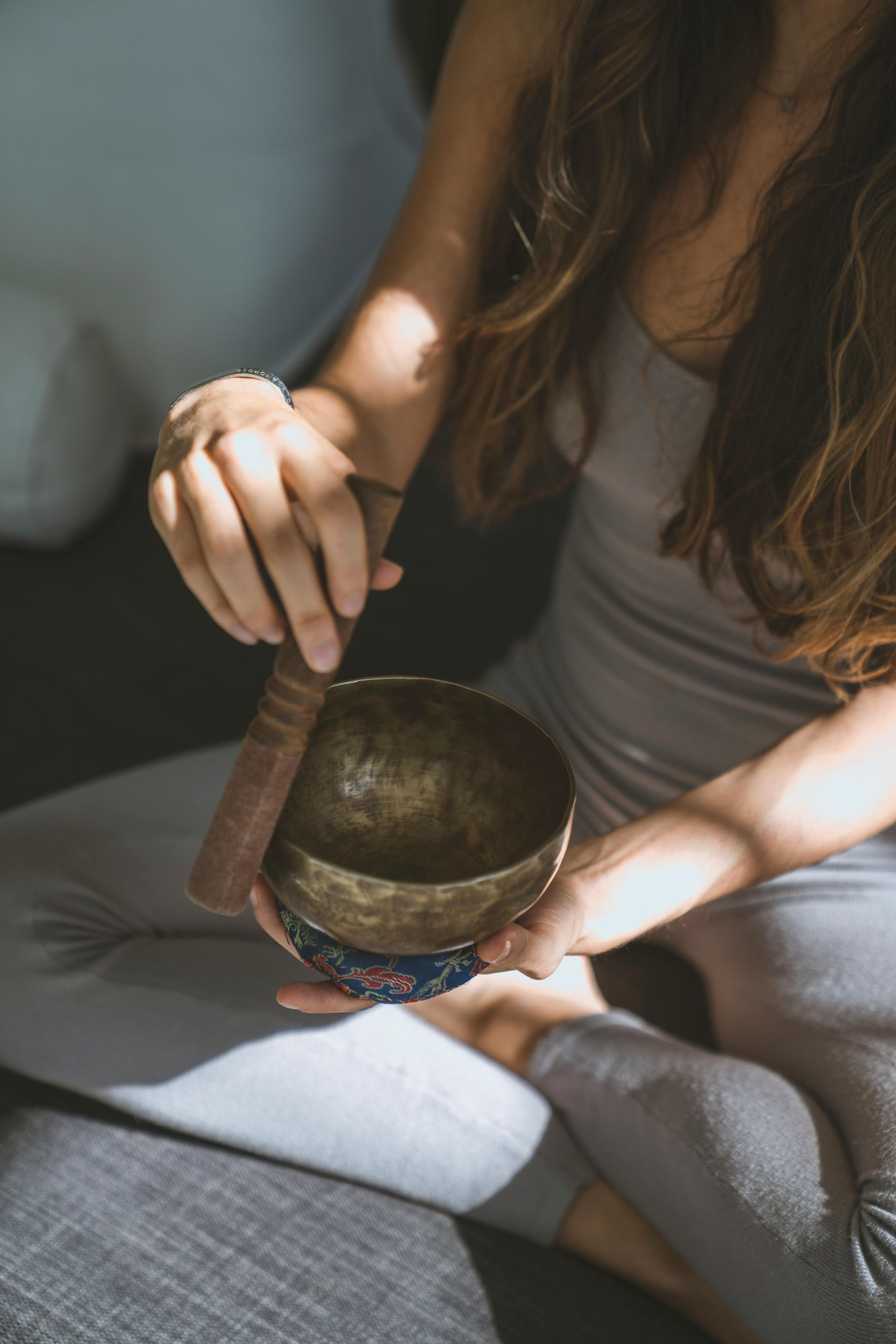 A woman is sitting on a couch holding a singing bowl.