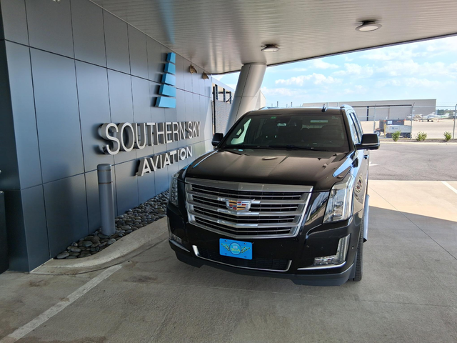 Black Cadillac Escalade parked in front of Southern Sky Aviation building.