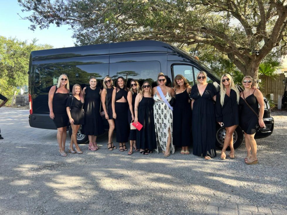 Group of women in black dresses pose with a black van.