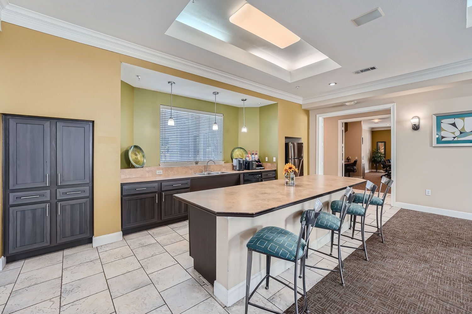 A kitchen with a large island and stools in a building.