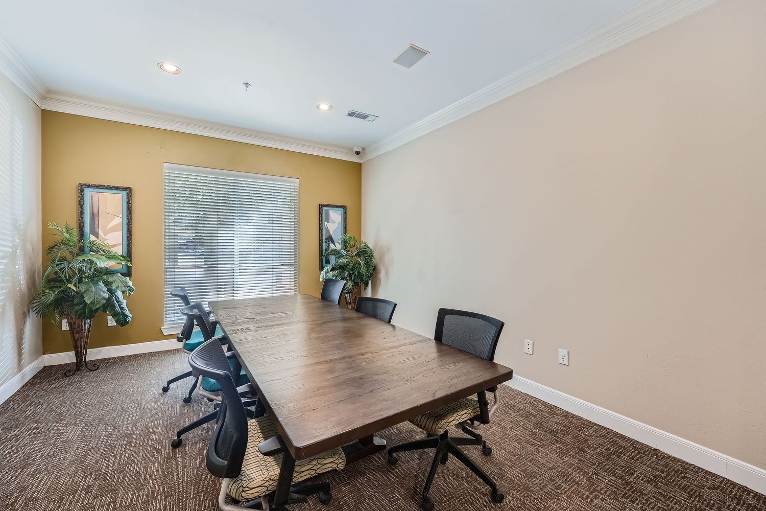 A conference room with a long wooden table and chairs.