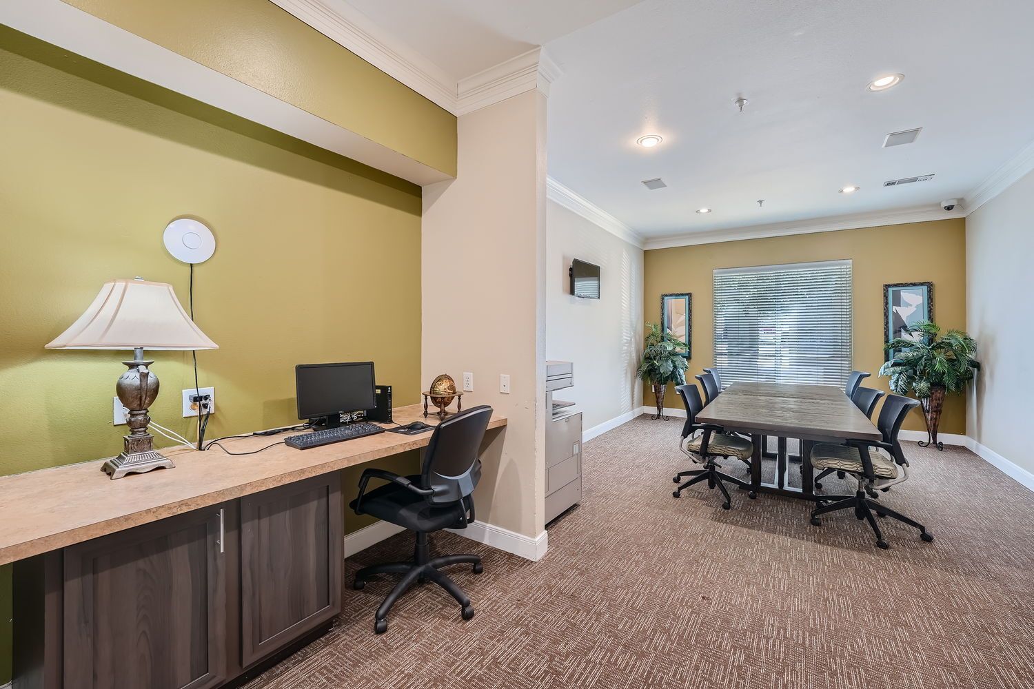 A room with a table and chairs and a desk with a computer on it.