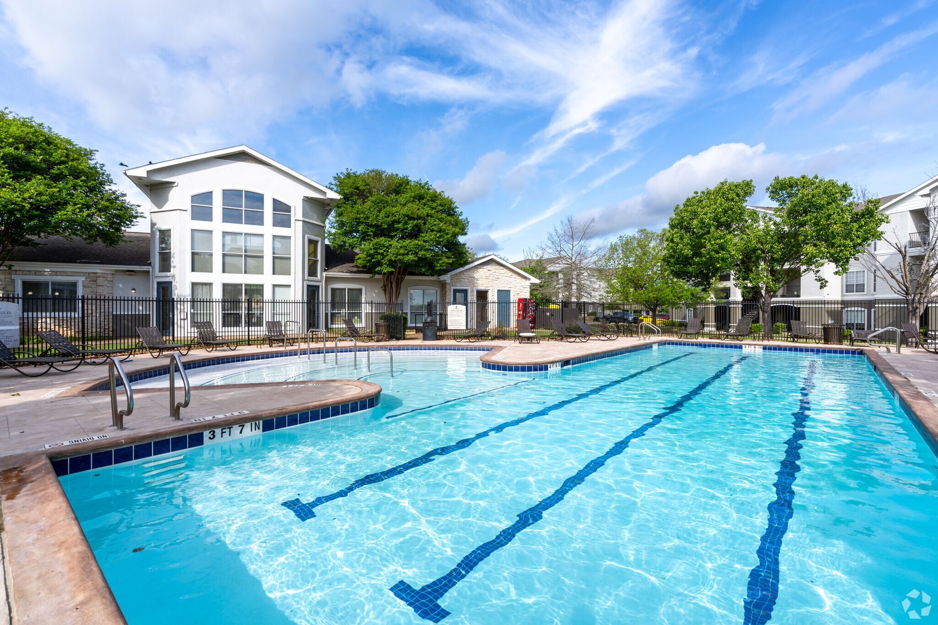 There is a large swimming pool in front of a building.