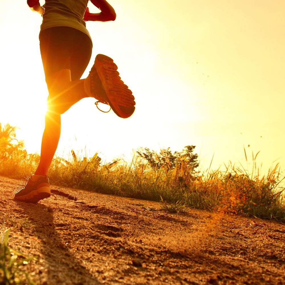 A person is running on a dirt road at sunset