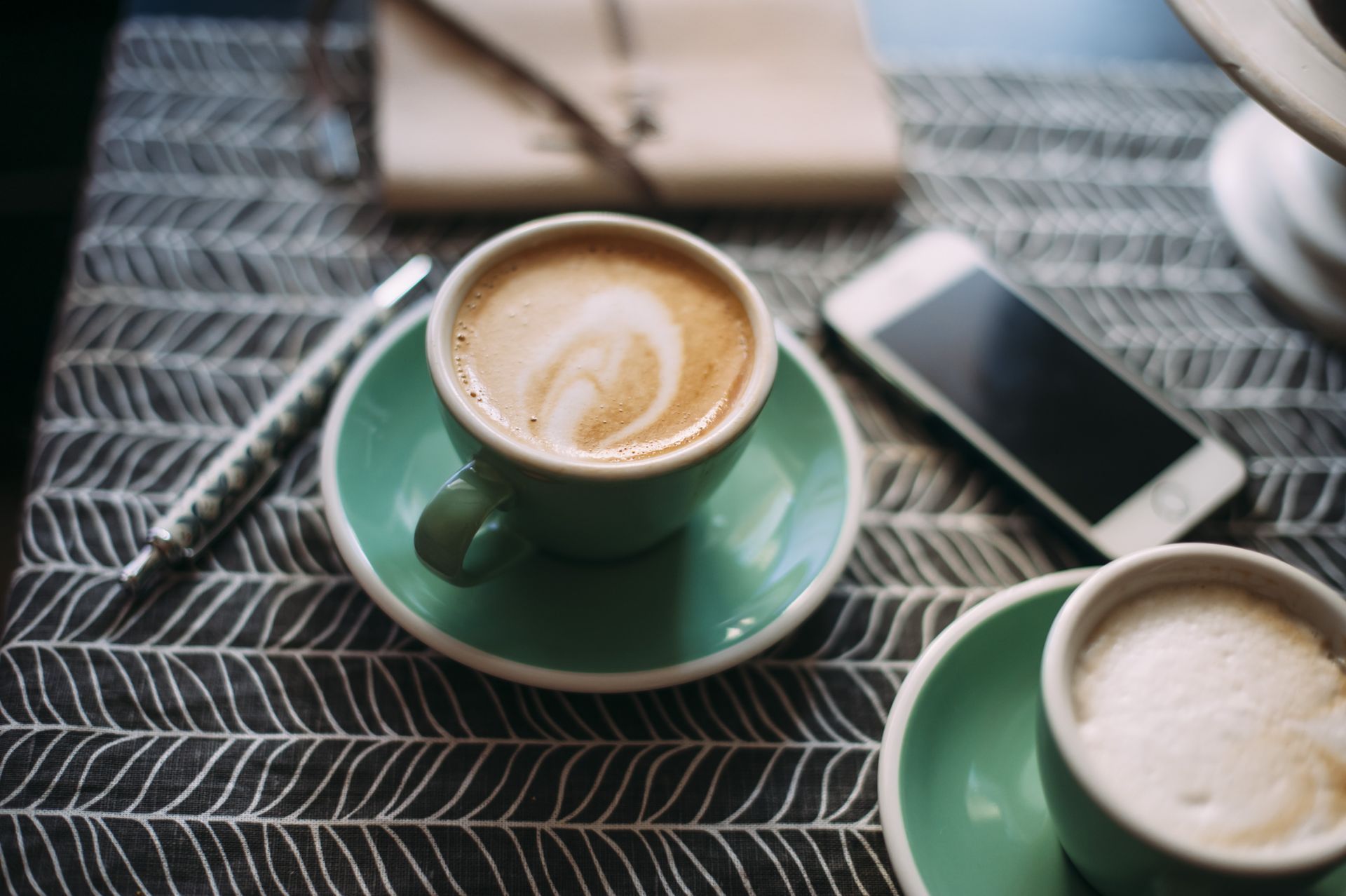 Two cups of coffee and a cell phone on a table