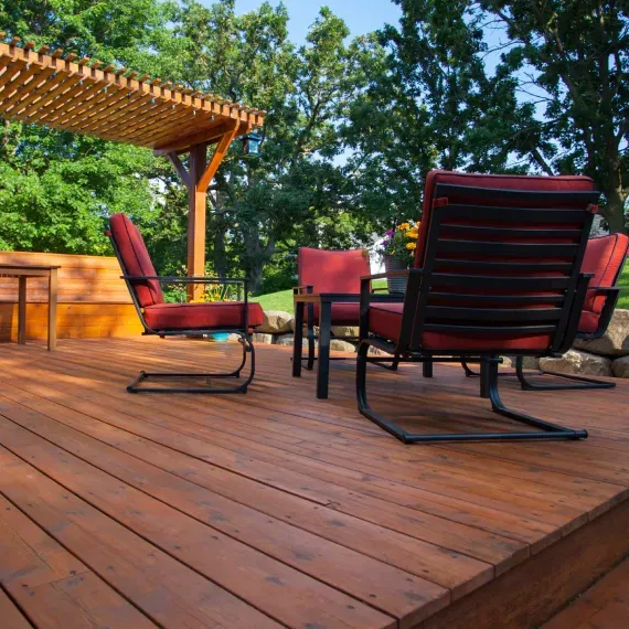 A wooden deck with chairs and a table under a pergola