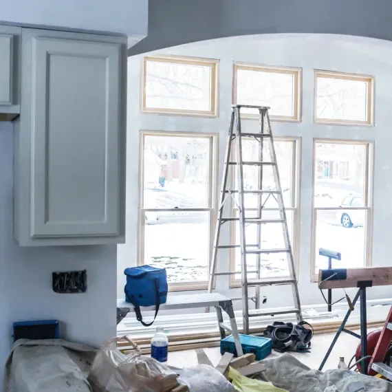 A kitchen under construction with a ladder and a blue bag