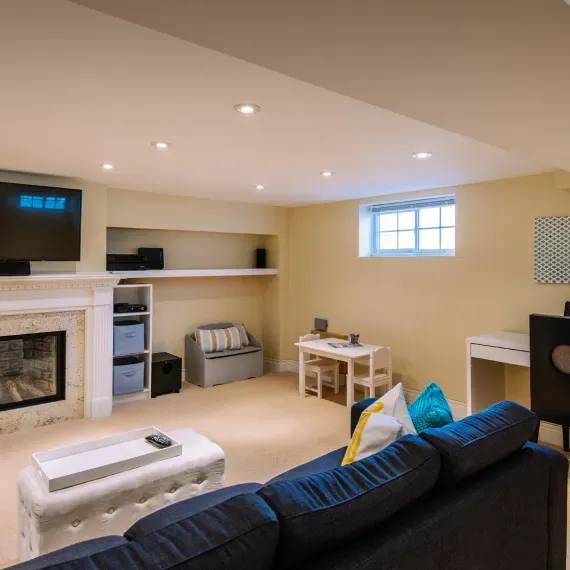 A living room with a blue couch and a fireplace