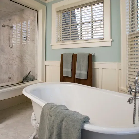 A bathroom with a tub and a window with blinds