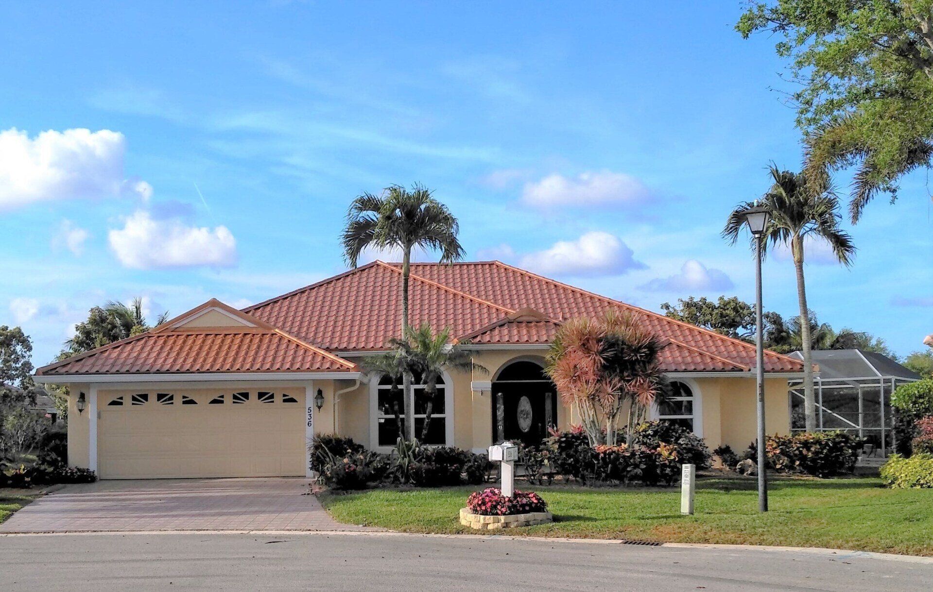 Jupiter FL Copper Penny Interlock Mediterranean Tile Metal Roofing System installed on a rancher with a palm tree in the front yard