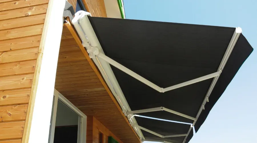 A black awning is hanging from the side of a house