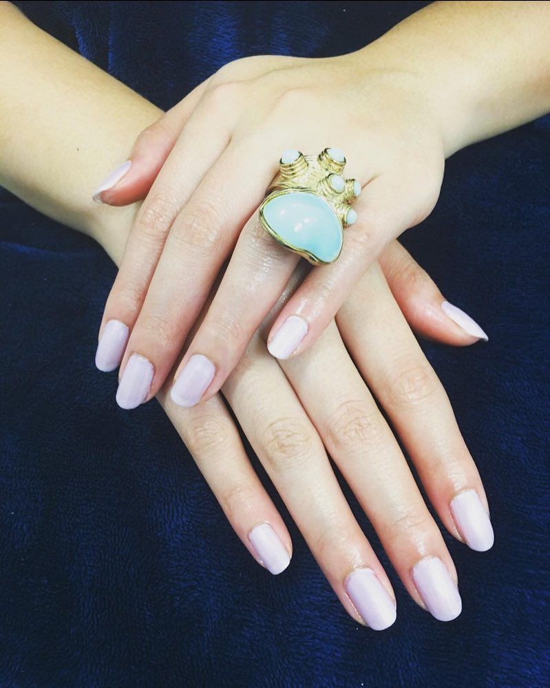 Woman's hands with light purple nail polish, wearing a large, ornate ring.