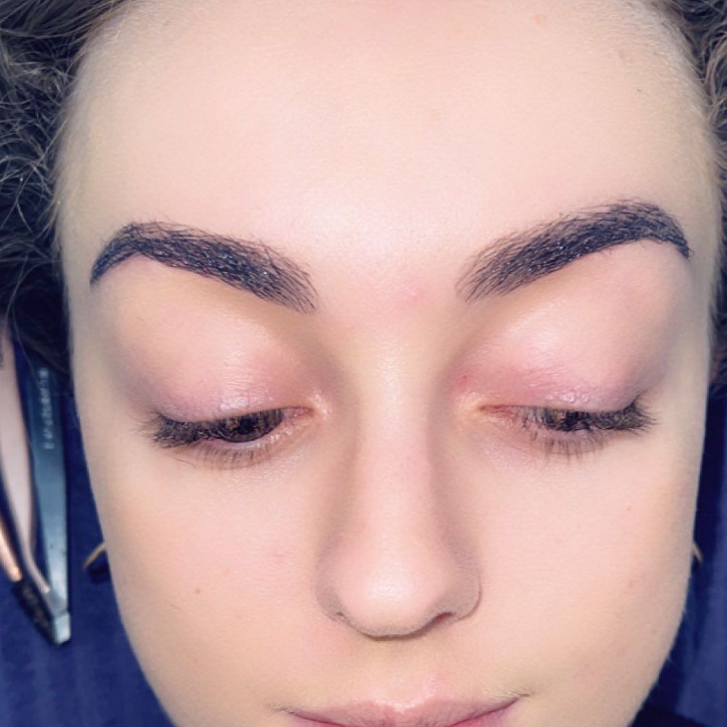 Woman with dark, filled-in eyebrows looking down, skin is pale pink.