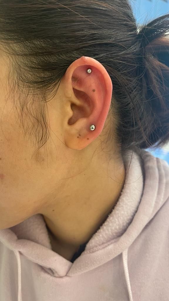Person with ear piercings: two studs visible on the ear.