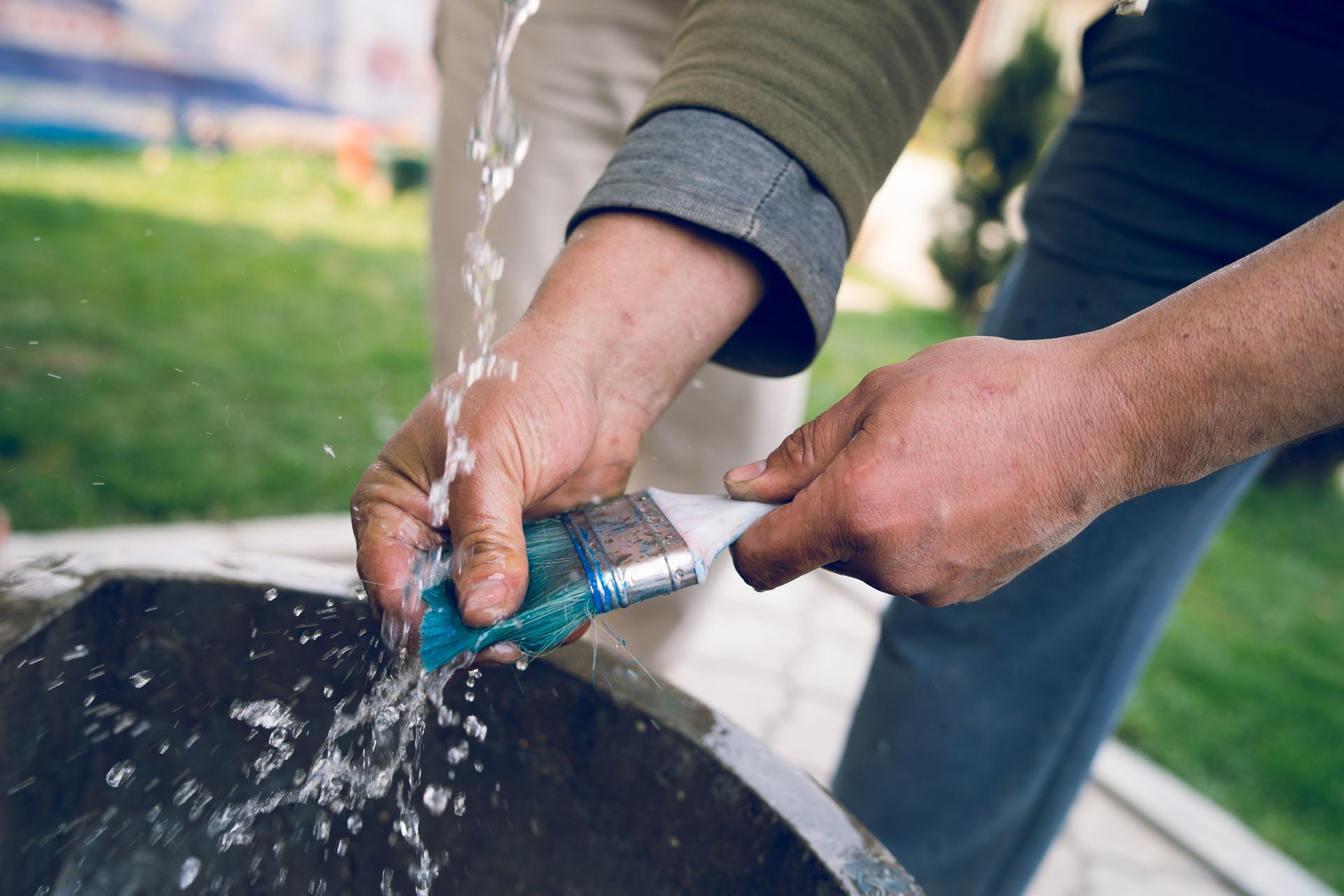 A person is washing a brush in a bucket of water.