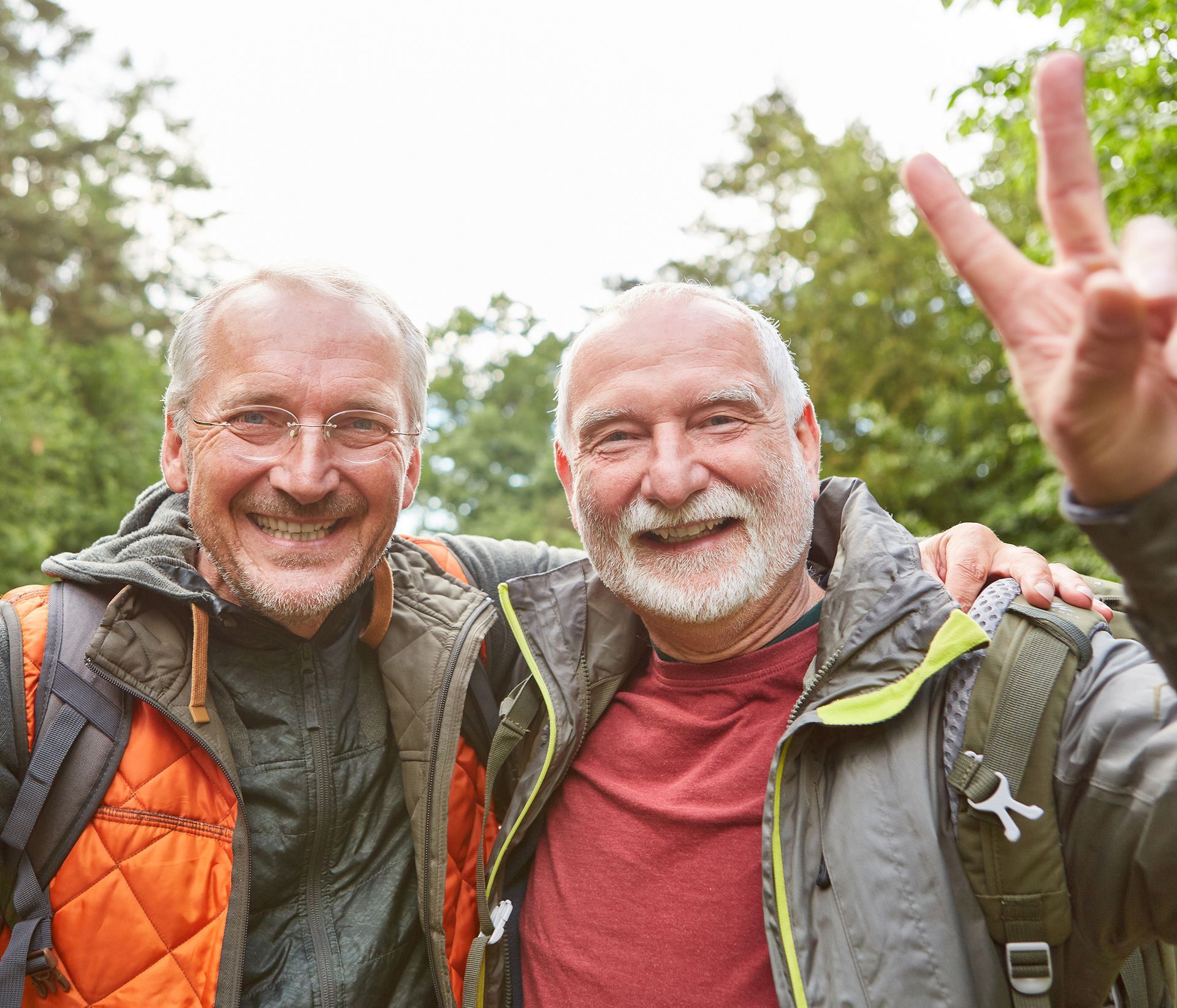 Two men are posing for a picture together and one of them is giving a peace sign.