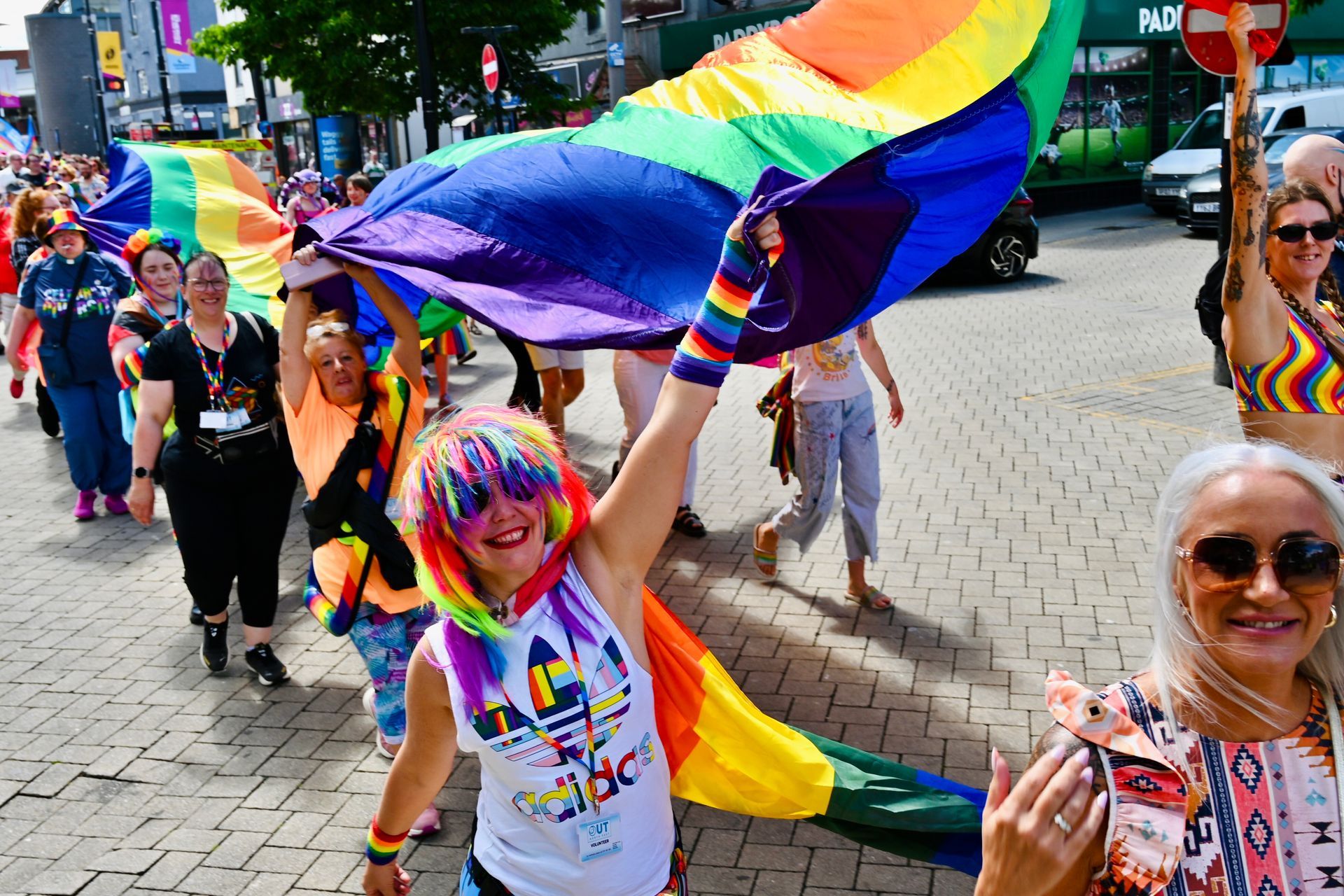 People celebrating in a street, holding and waving a rainbow flag.