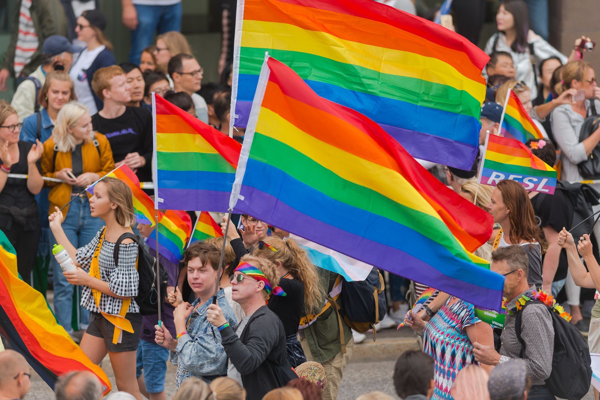 a crowd of people are holding rainbow flags in a parade .
