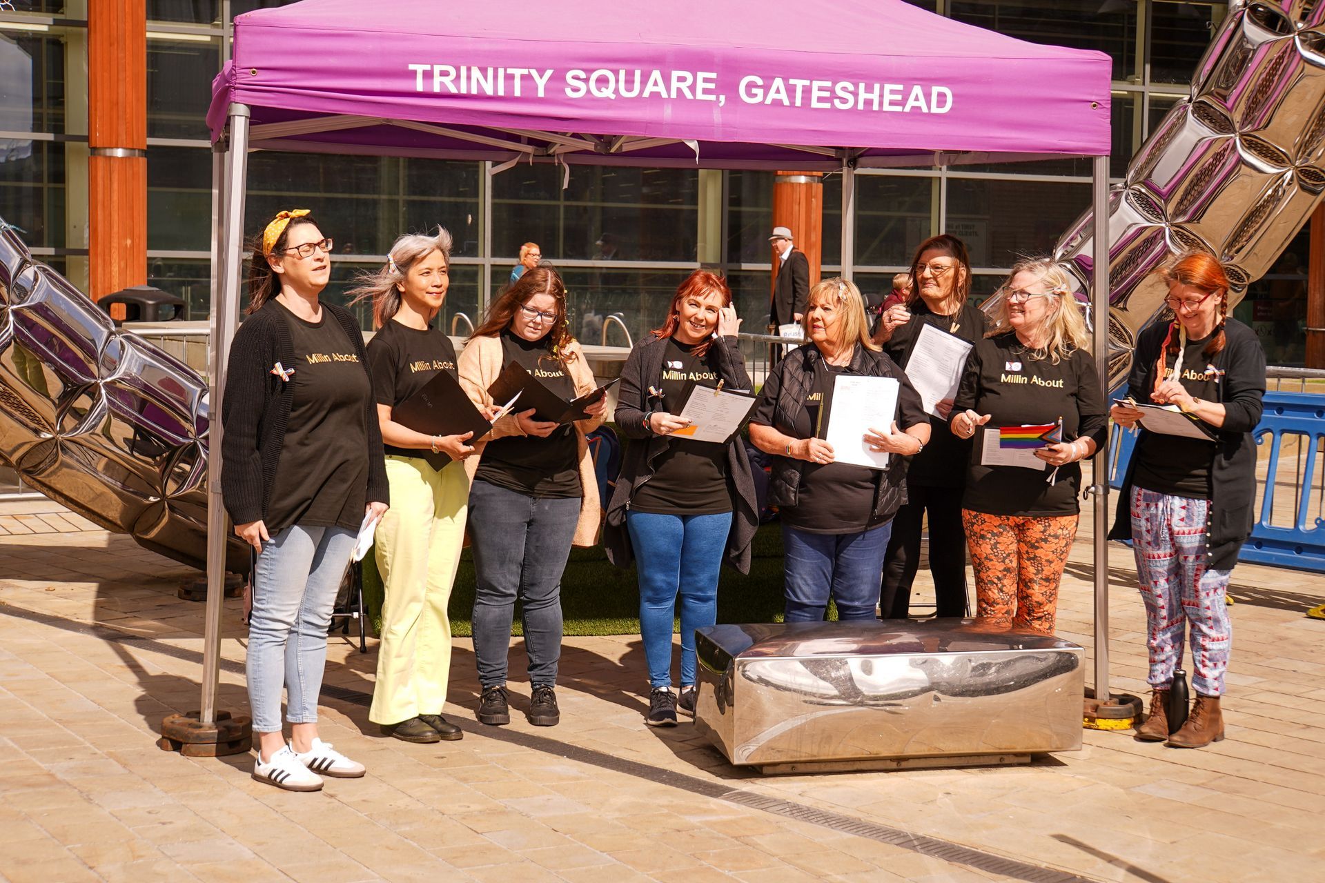 A group of women are singing under a purple tent.