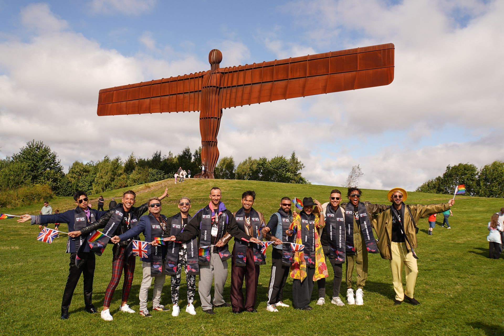 A group of people are posing for a picture in front of a statue of an angel.