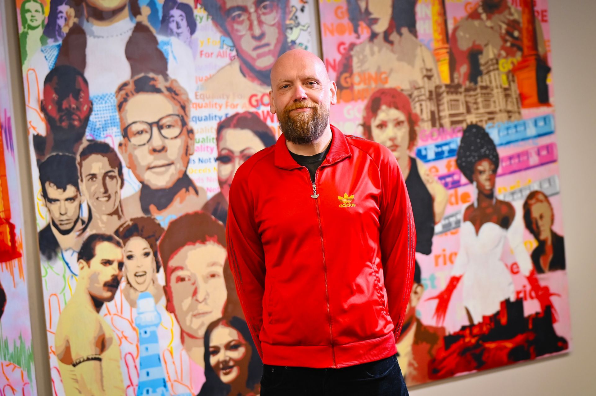 Person looking at a wall covered with photos and messages, likely related to LGBTQ+ pride.