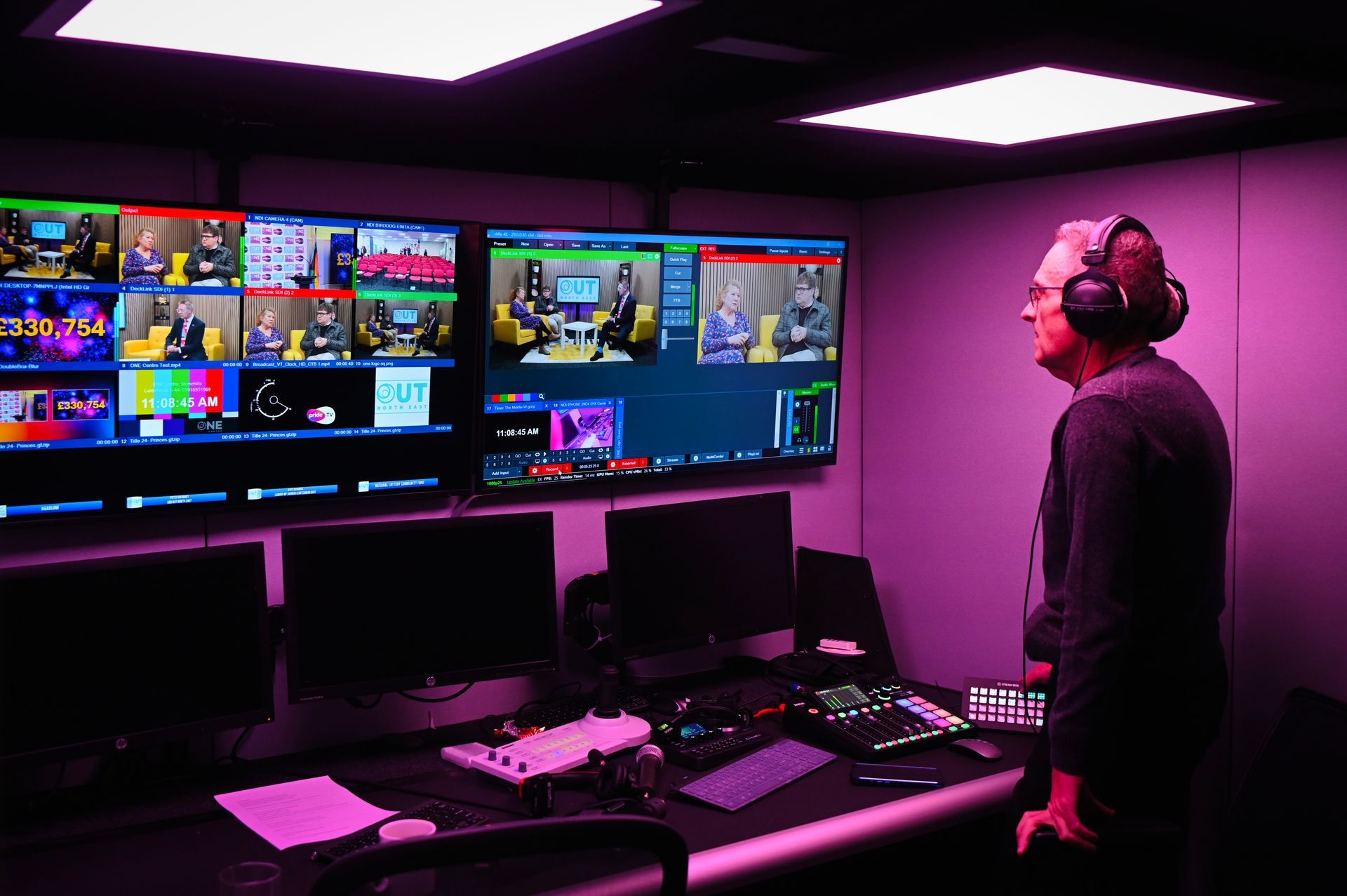 Microphone in a recording studio, person visible through the window in the background.