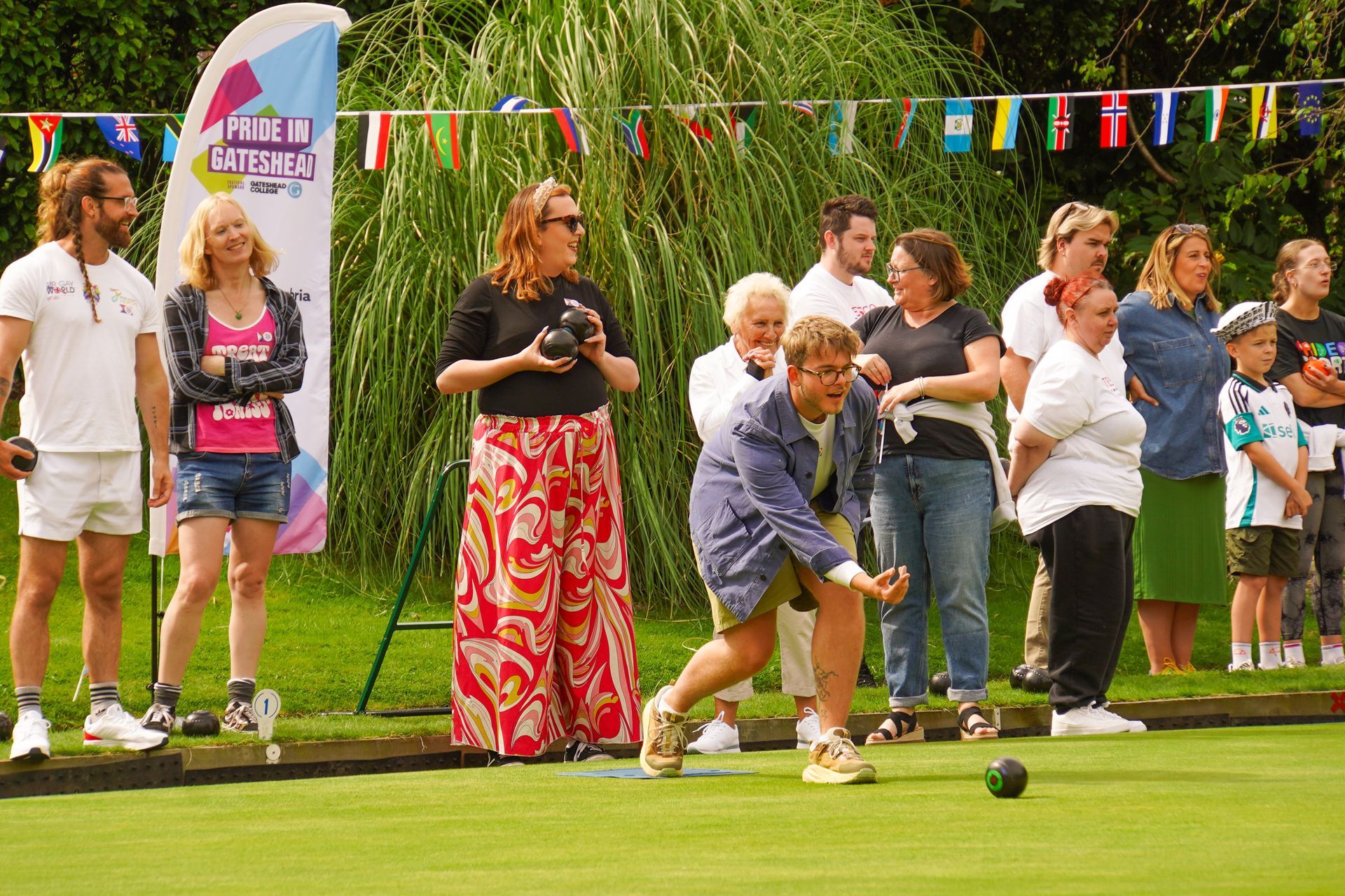 A group of people are watching a man throw a bowling ball.