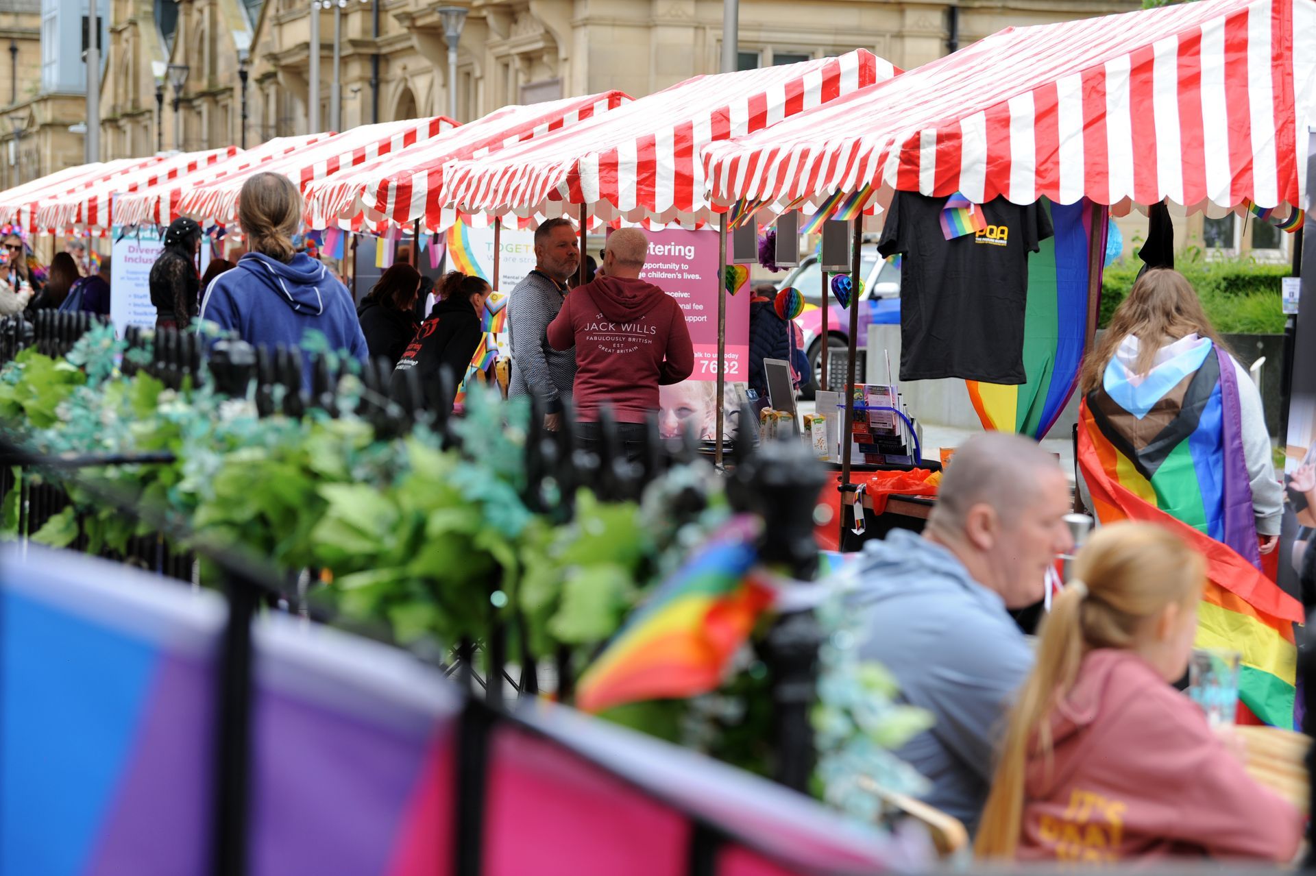 A group of people are standing in front of a row of striped tents.
