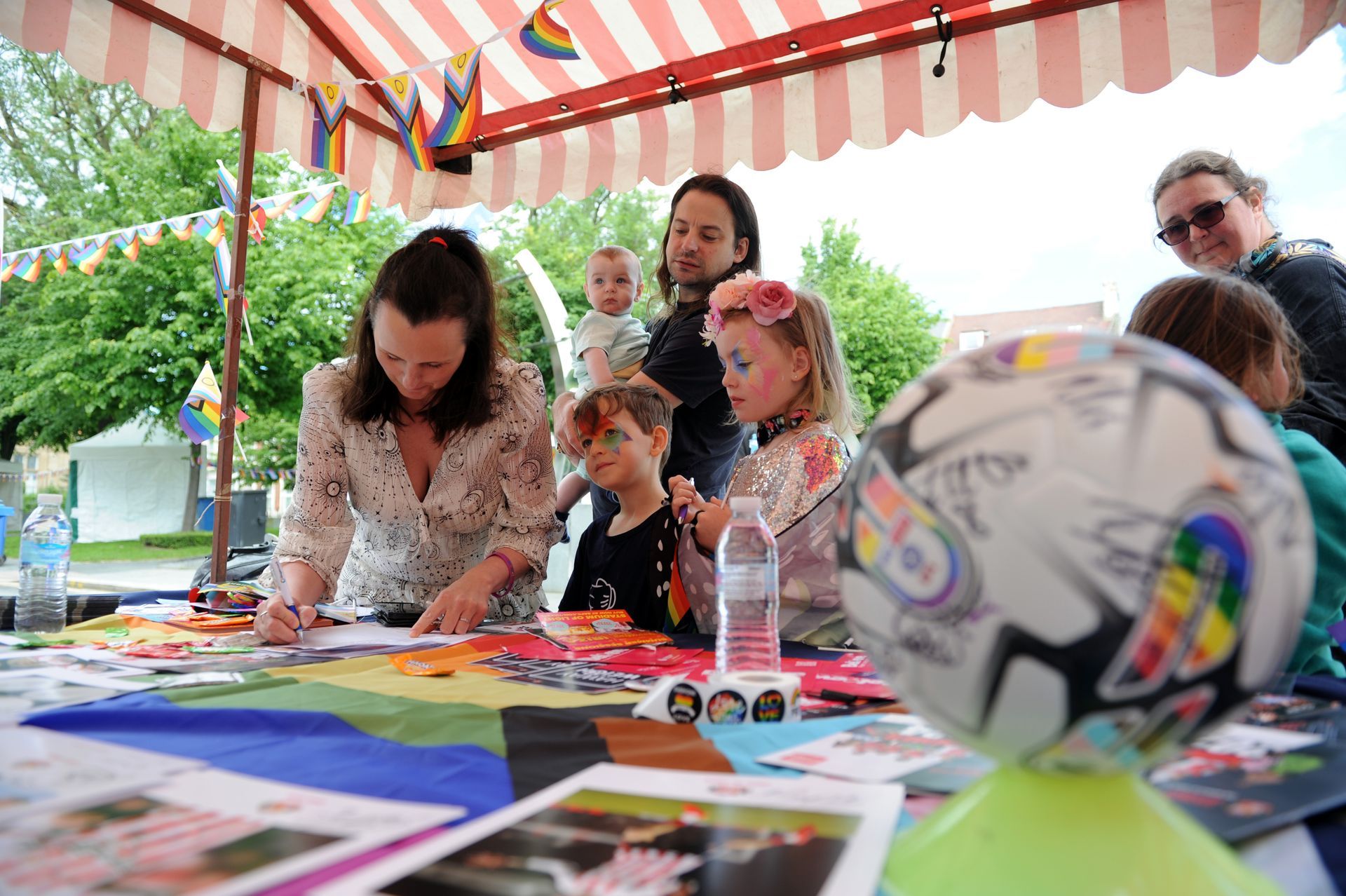 A group of people are sitting around a table with a soccer ball in the foreground.