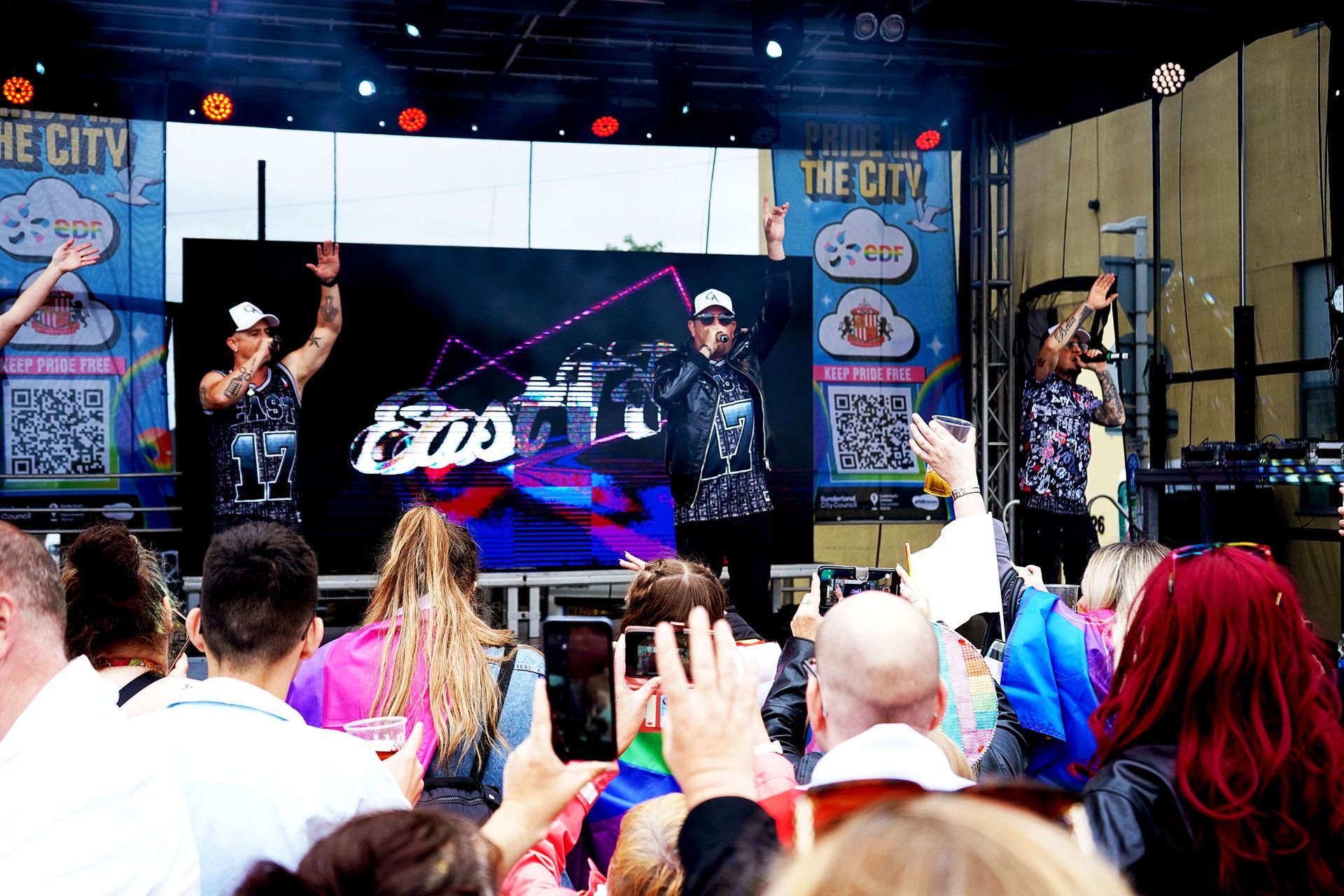 A group of people are standing in front of a stage at a concert.