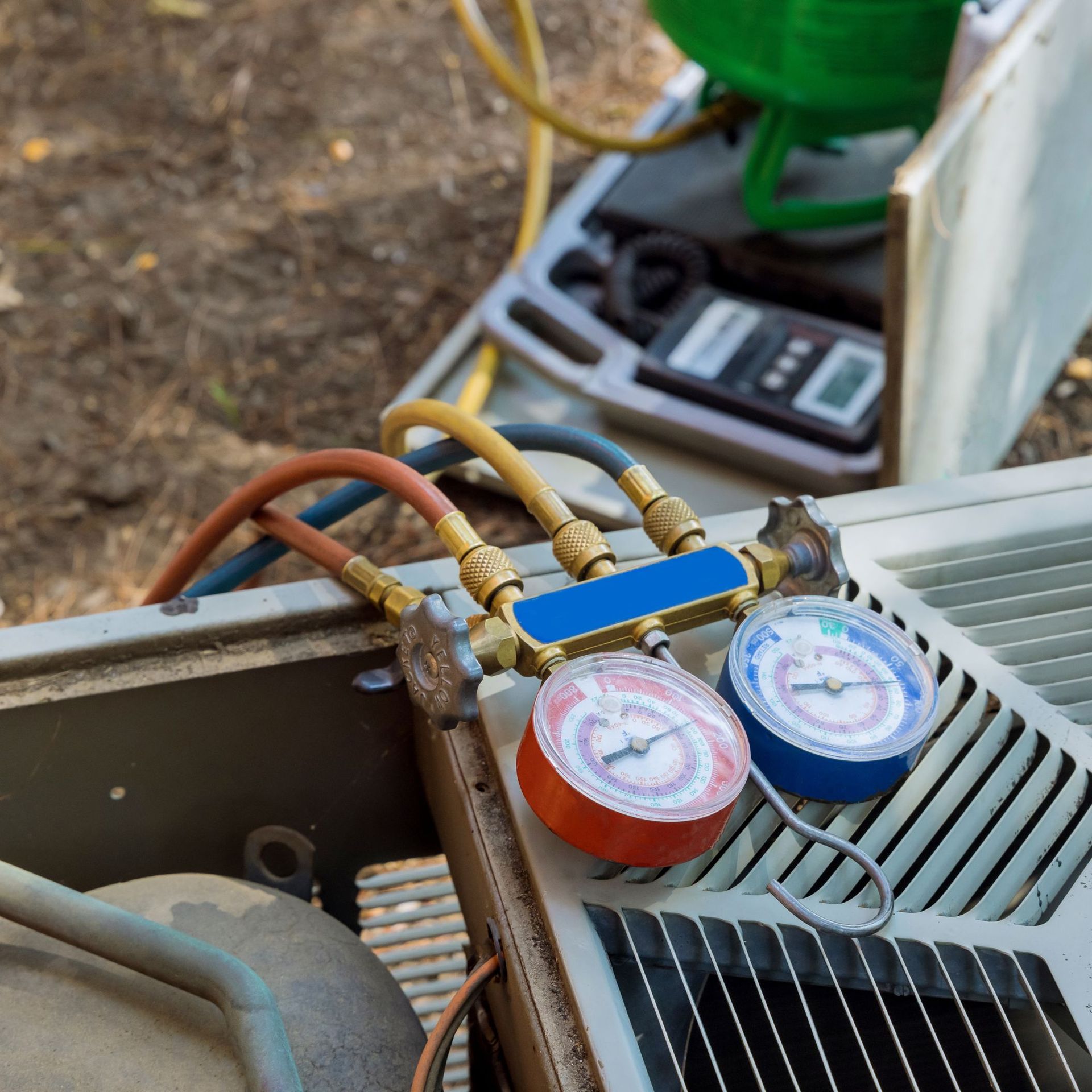 HVAC gauges connected to an air conditioning unit, red and blue gauges showing pressure.