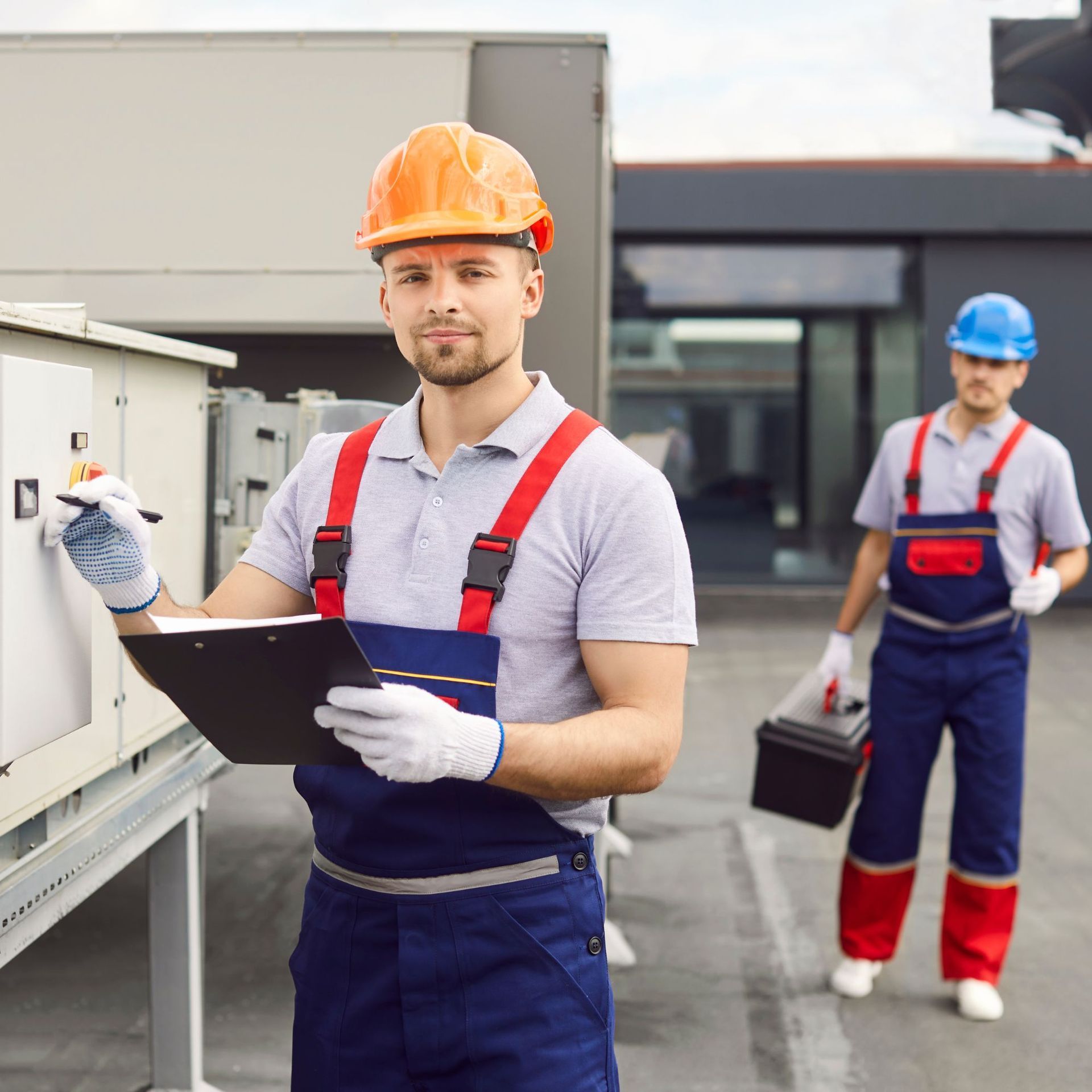 Two construction workers in hard hats reviewing blueprints at a construction site.