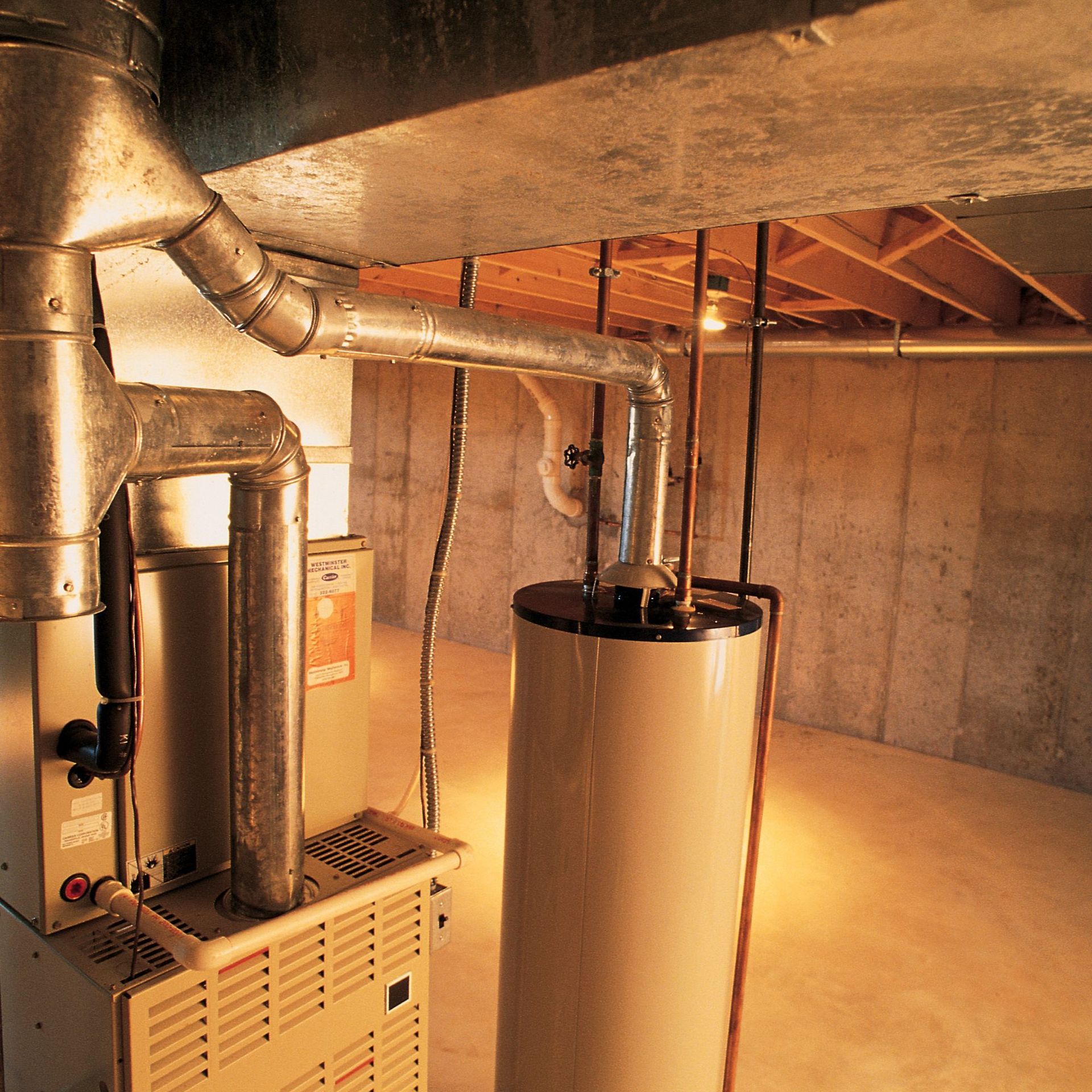 Above Comfort Mechanical LLC - Furnace and water heater in a basement, with ductwork and pipes.
