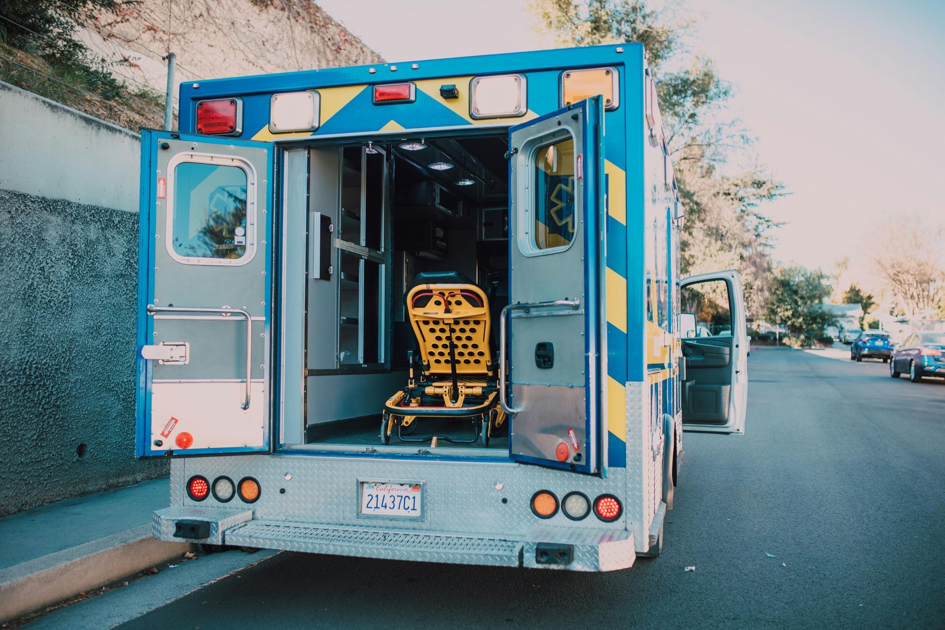 Ambulance with open doors on a street, revealing medical equipment inside.