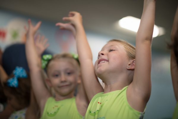 A little girl is doing a handstand on an orange mat.