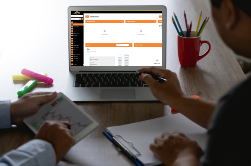 Two people are sitting at a desk looking at a laptop