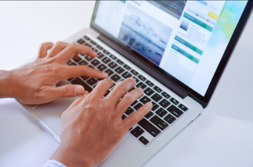 A person is typing on a laptop with their fingers