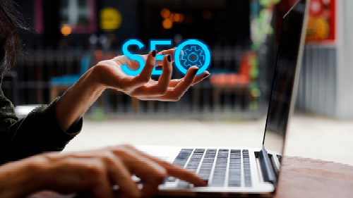 A woman is using a laptop computer and holding a sign that says seo.