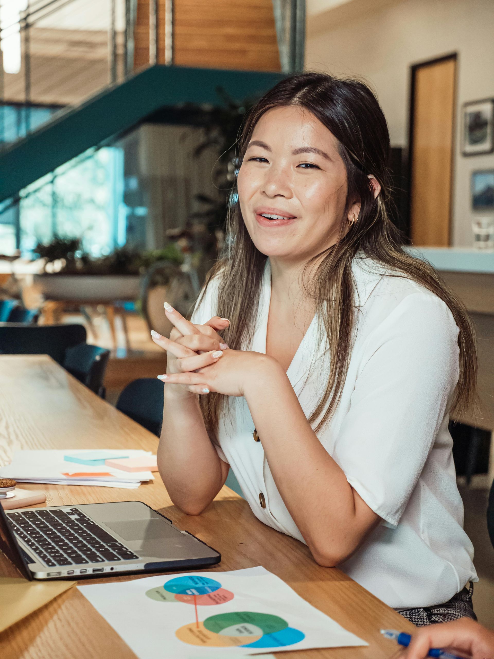 A woman is sitting at a table with a laptop and papers.