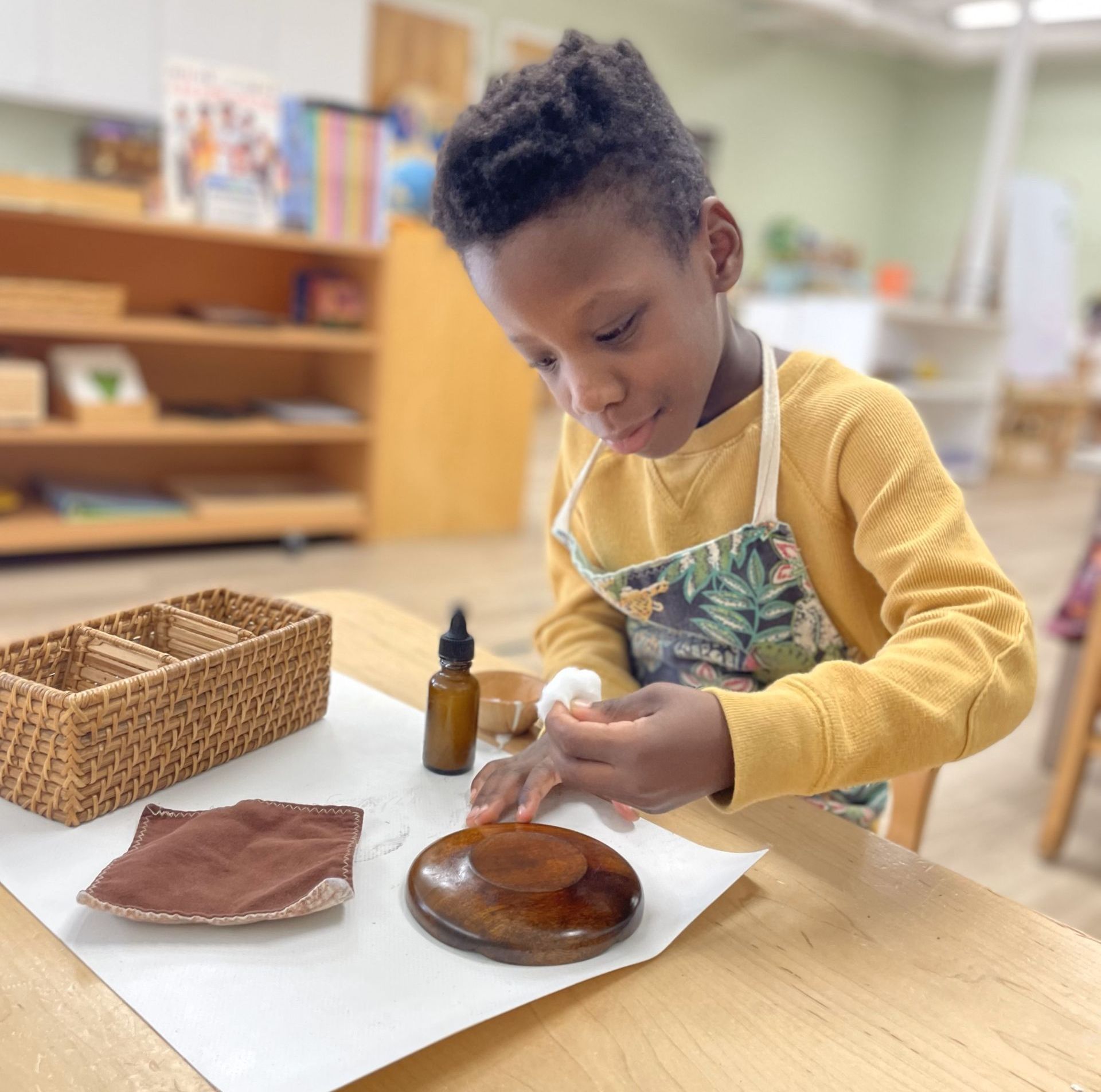 A young boy is sitting at a table playing with a piece of wood.